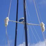 They're called "baggy wrinkles".  Fashioned from old rope, they are braided on either side of the spreaders, preventing chafe on the headsail.  They're typical of classic old schooners.